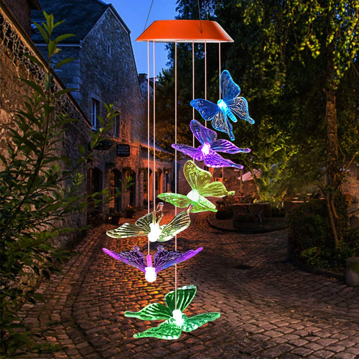 A collection of color-changing butterfly solar lights adorning a vibrant garden bed, enhancing outdoor decor.