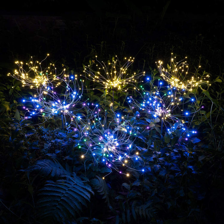 Firework-shaped solar lights glowing against a dark blue sky, perfect for festive outdoor lighting.