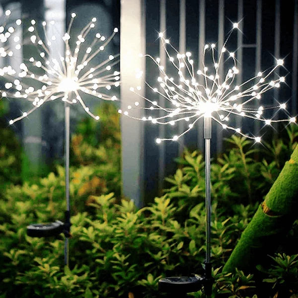 Assortment of solar firework lights in various stages of illumination in an outdoor garden setting.