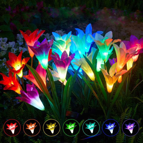 Close-up of a waterproof solar lily flower stake light with changing LED colors in a garden bed.