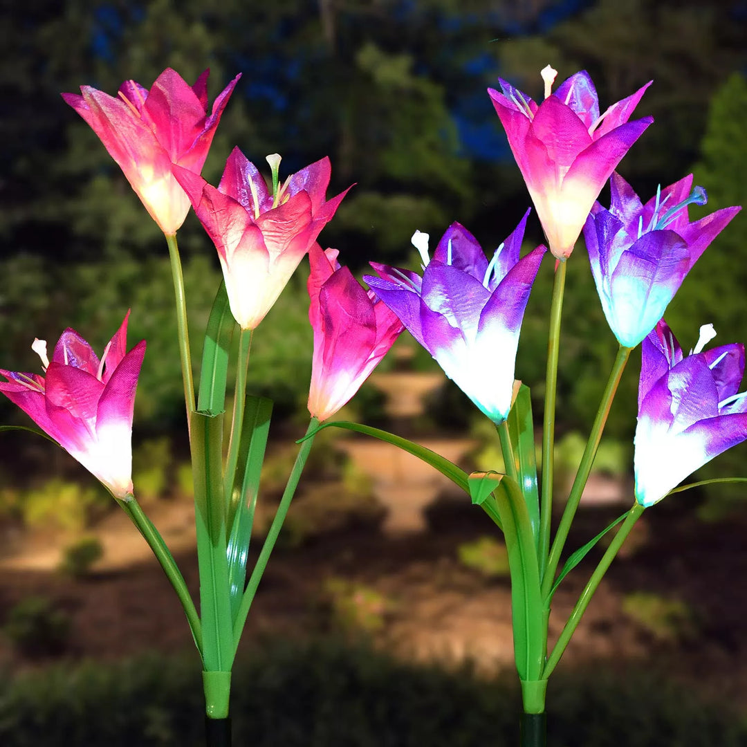 A set of multicolored solar LED lily flower lights enhancing outdoor garden decor at night.