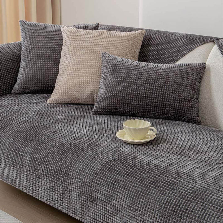 Woman relaxing on a couch covered with a cozy Textured Waffle Chenille Furniture Protector.