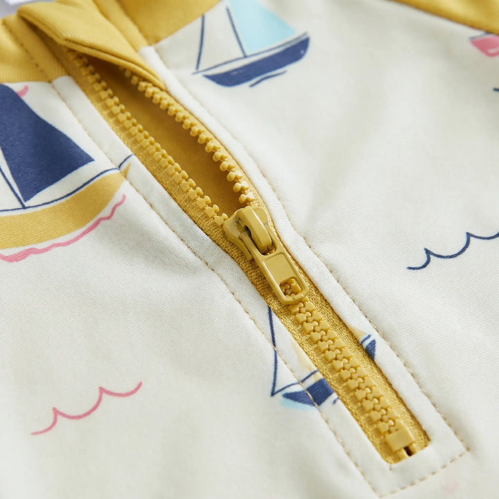 Close-up of UPF 50+ sun protection toddler swimwear set, showing rash guard, shorts, and swim hat fabric.