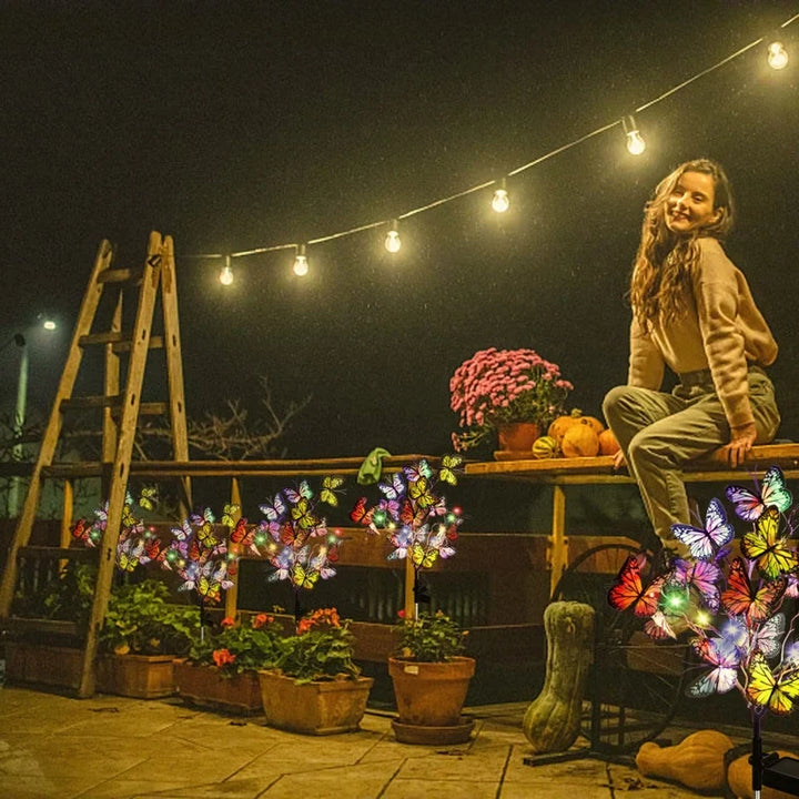 A pair of waterproof solar butterfly lights nestled amongst flowers, providing charming landscape lighting.