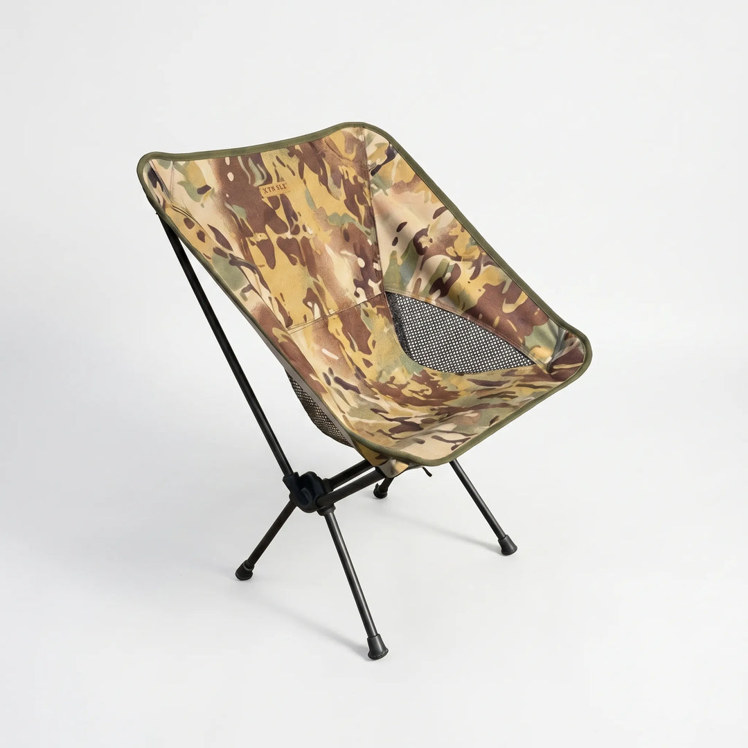 Person relaxing in an ultralight folding camping chair by a lake, enjoying comfortable outdoor seating on a sunny day.