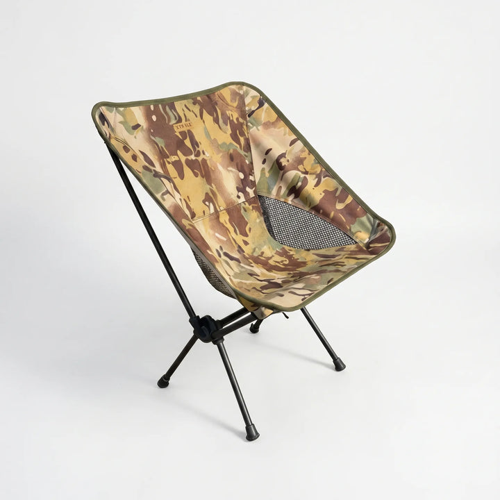Person relaxing in an ultralight folding camping chair by a lake, enjoying comfortable outdoor seating on a sunny day.