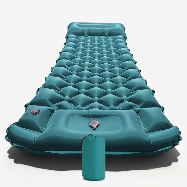 Hiker resting on an inflatable camping sleeping mat with built-in pillow & pump in a scenic outdoor setting.