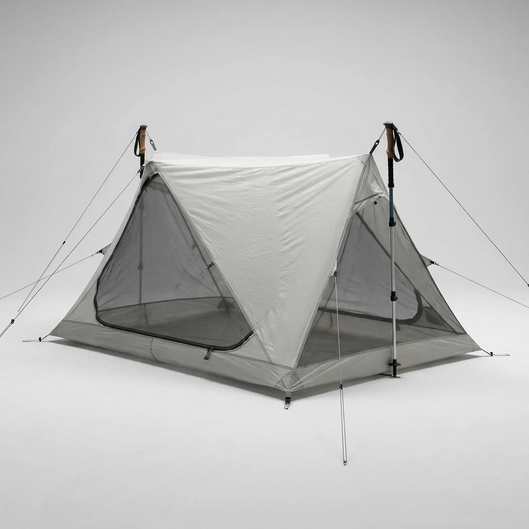 Lightweight one-person mesh tent in a forest, set up with trekking poles for effective outdoor insect protection.