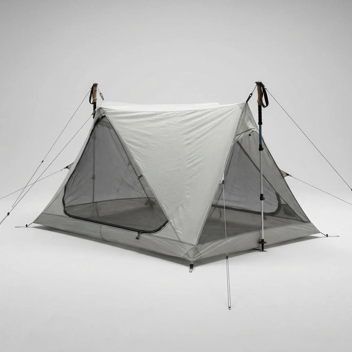 Lightweight one-person mesh tent in a forest, set up with trekking poles for effective outdoor insect protection.