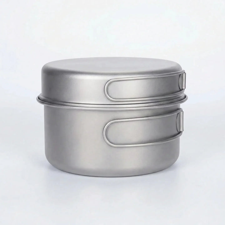 Close-up of ultralight titanium pot with folding handle, perfect for compact backpacking and outdoor cooking.