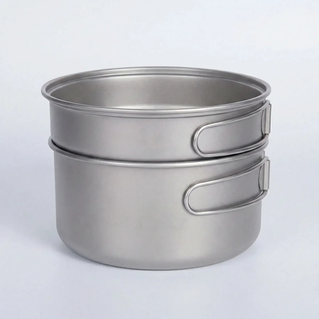 Complete ultralight titanium pot & pan set with folding handles, ideal for backpacking, camping, & hiking meals.