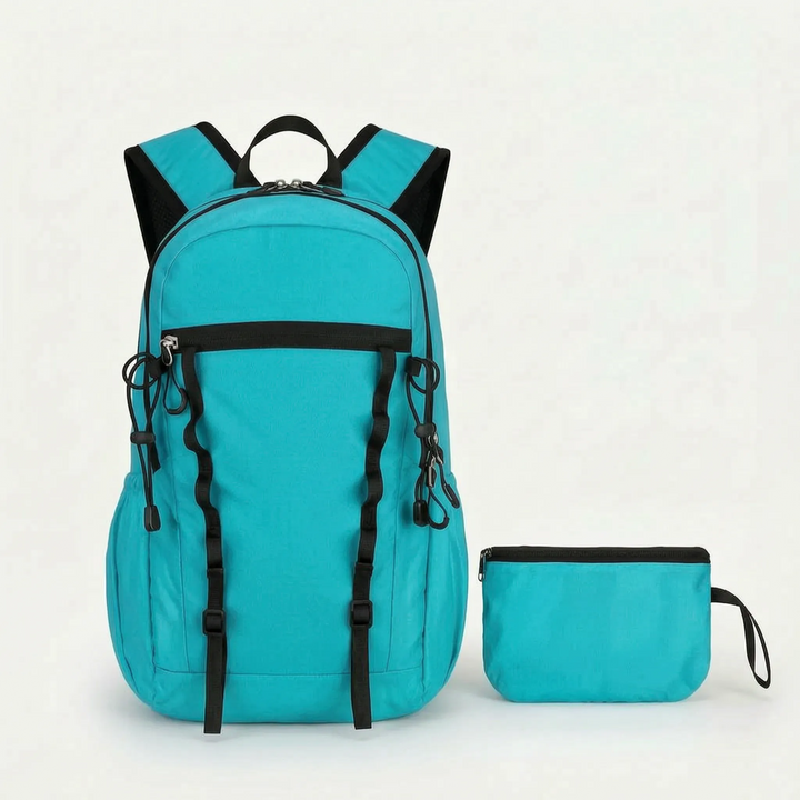Person unpacking a cyan foldable hiking daypack from its pouch, preparing for a lightweight outdoor adventure.
