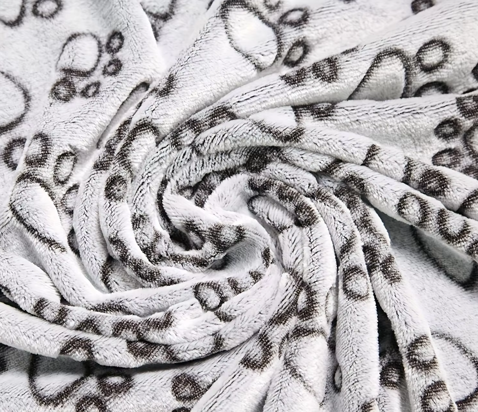 Machine washable gray pet blanket, paw pattern, provides pet comfort on furniture