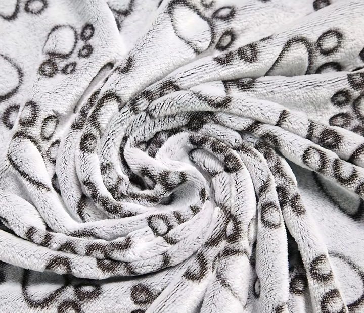 Machine washable gray pet blanket, paw pattern, provides pet comfort on furniture