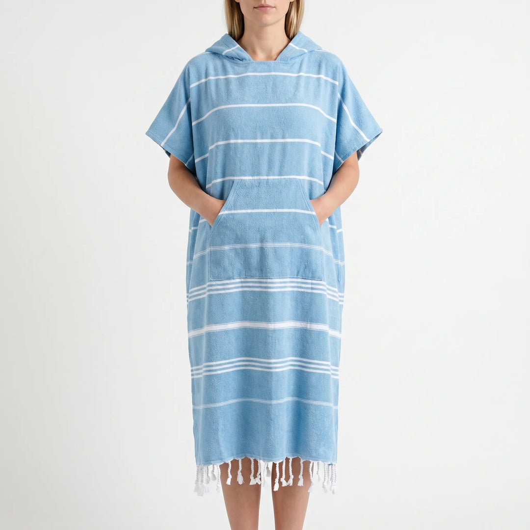 Model wearing a hooded surf changing poncho on a sunny beach, perfect for quick changes.