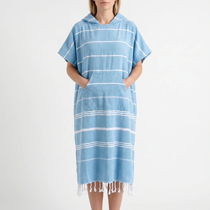 Model wearing a hooded surf changing poncho on a sunny beach, perfect for quick changes.