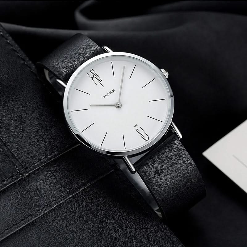 Close-up of a minimalist analog watch dial, featuring clear markers and a finely crafted leather strap.