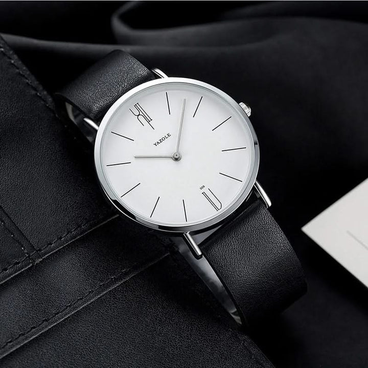 Close-up of a minimalist analog watch dial, featuring clear markers and a finely crafted leather strap.