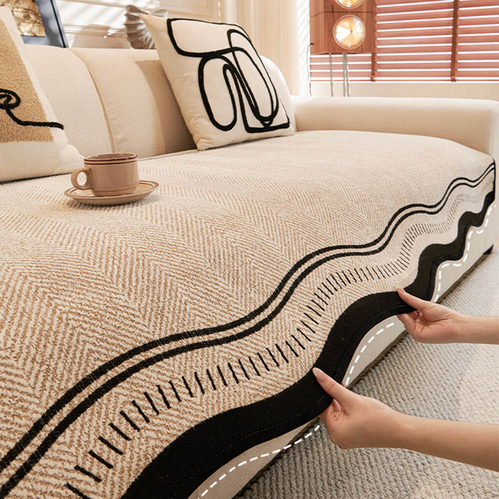 Close-up of the herringbone pattern on a chenille sofa protector with stylish wavy edges, neutral color.