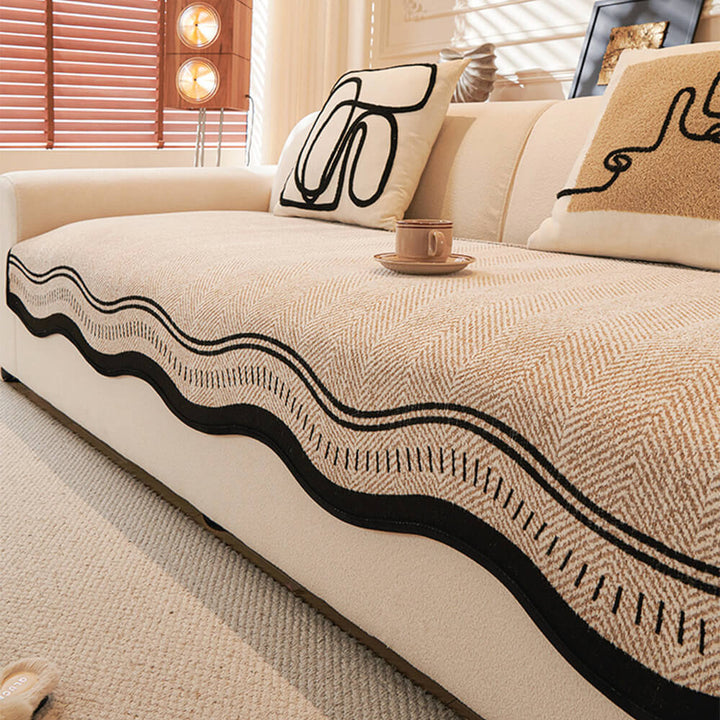 Chenille sofa cover with herringbone texture and distinctive wavy edge, showcasing its non-slip backing.