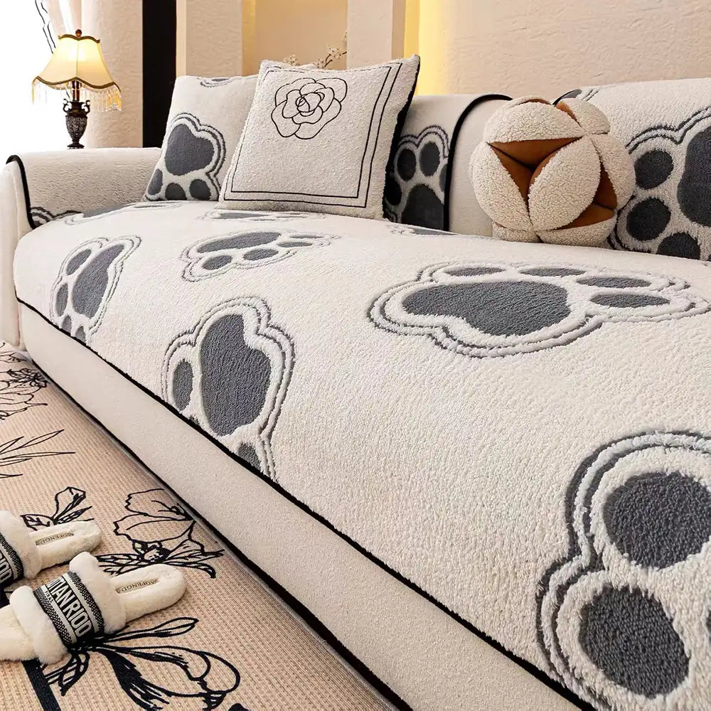 Washable polar fleece sofa protector with black paw prints on a light couch