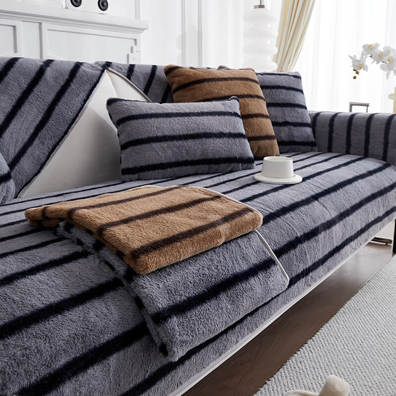 Full view of a living room sofa with a striped faux rabbit fur protector, modern decor