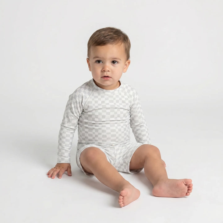 Happy toddler wearing a unisex long sleeve sun protection swimsuit set while playing in the water.