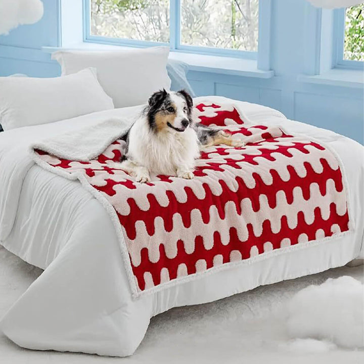 Unisex pet blanket on a sofa, providing waterproof protection and comfort with sherpa fleece for pets.