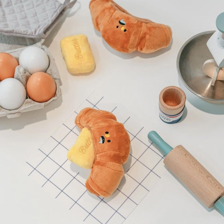 Interactive croissant dog toy, yellow plush, a squeaky pet accessory for playful animals.