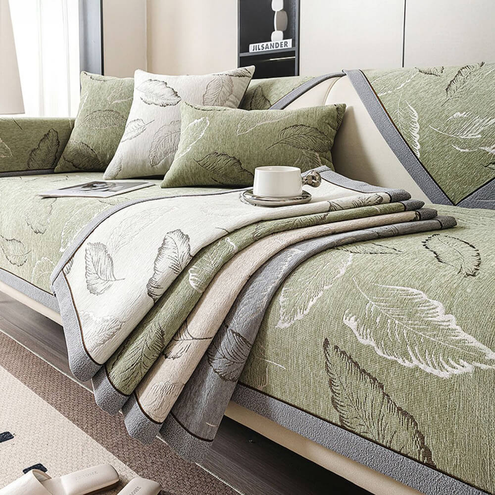 Full view of a living room with a universal chenille couch cover in a leaf pattern protecting the sofa.
