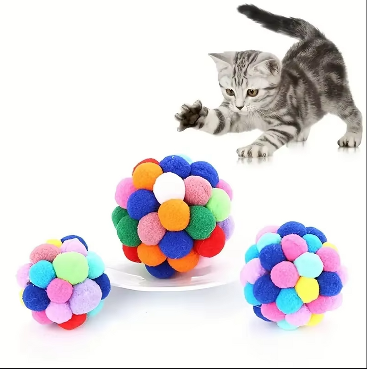 Three different colored pompom cat toy balls arranged in a playful pile, soft interactive feline fun.