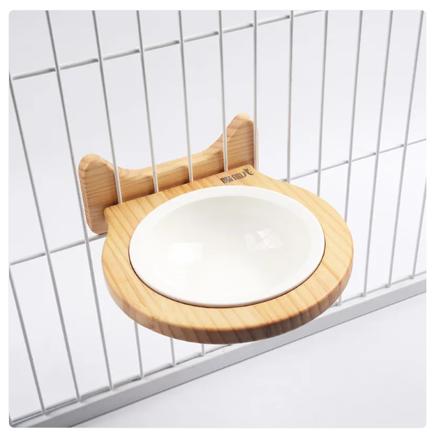 Close-up of a wall mounted cat feeder, showing the cloud design wooden frame and ceramic bowl