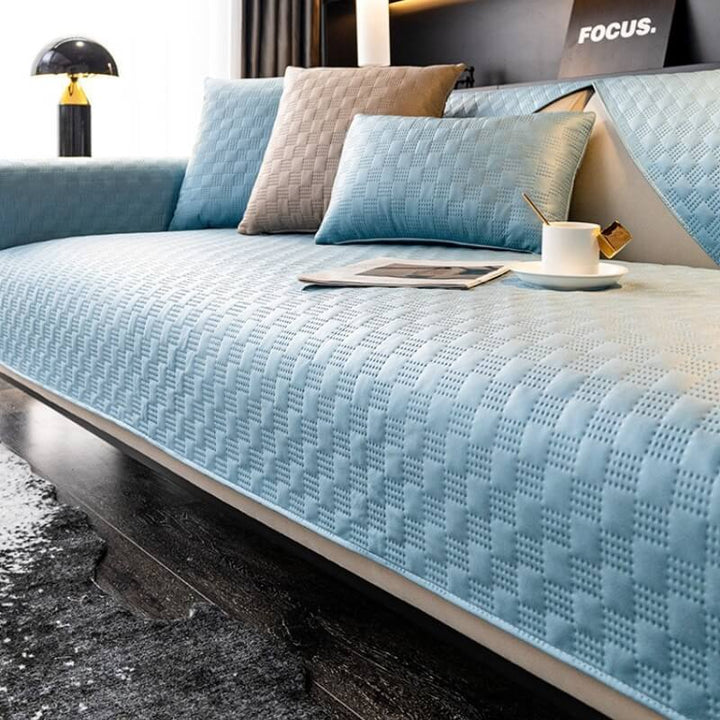 A child and pet-friendly faux leather sofa cover in a light blue, offering complete furniture protection.