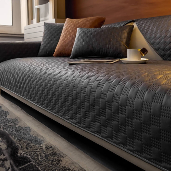Contemporary home decor featuring a sleek, waterproof faux leather couch cover in charcoal grey.