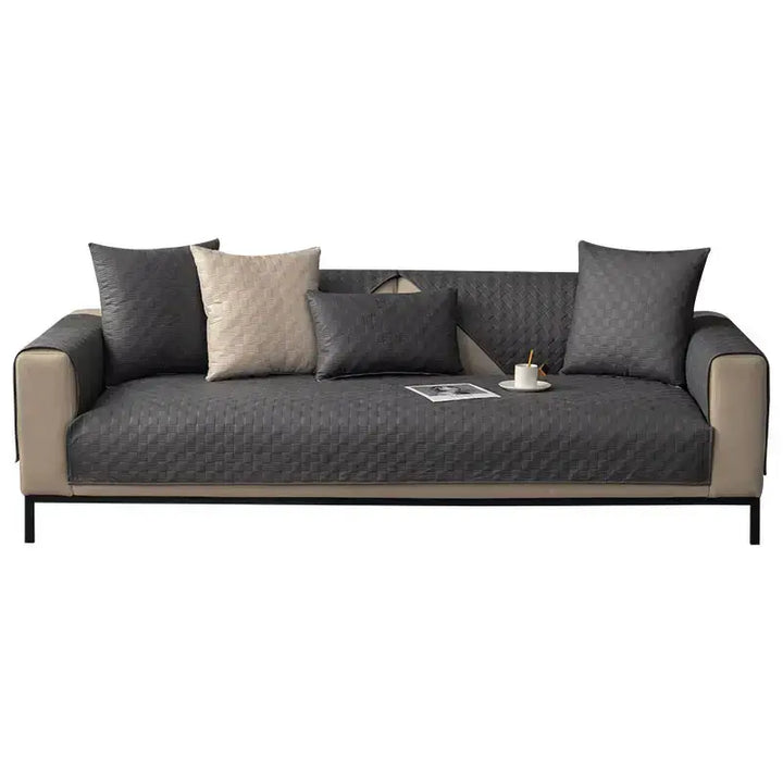 Full view of a living room with a faux leather sofa cover protecting a large U-shaped sectional from spills.