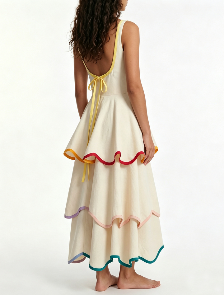 Sleeveless white maxi dress featuring elegant tiers and a playful rainbow ruffle trim. Women's vibrant summer fashion.
