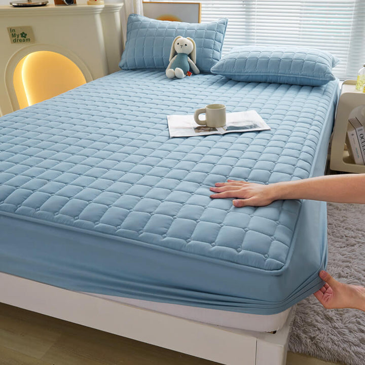 White waterproof mattress protector with fitted sheet design, showcasing elasticized edges for secure fit.