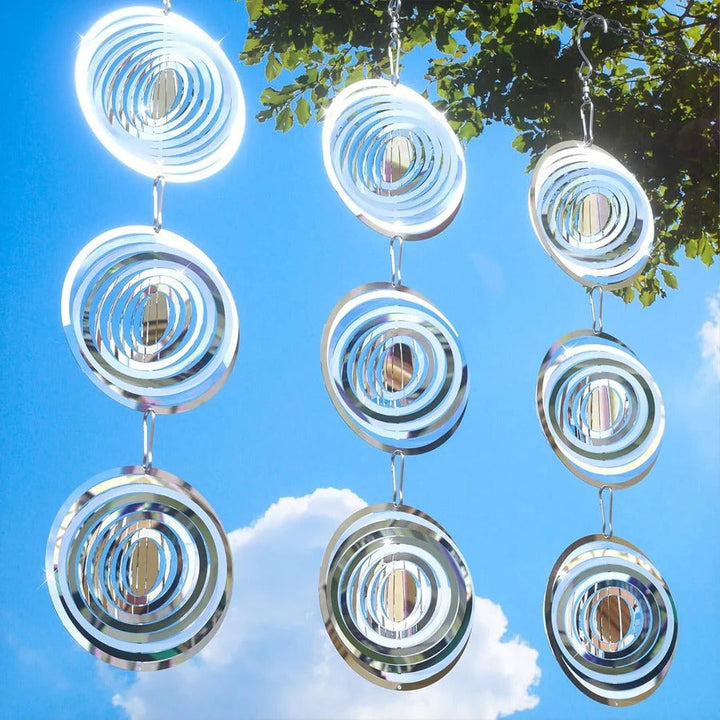 Wind-powered reflective bird deterrent device rotating in a garden, protecting fruit trees from pests