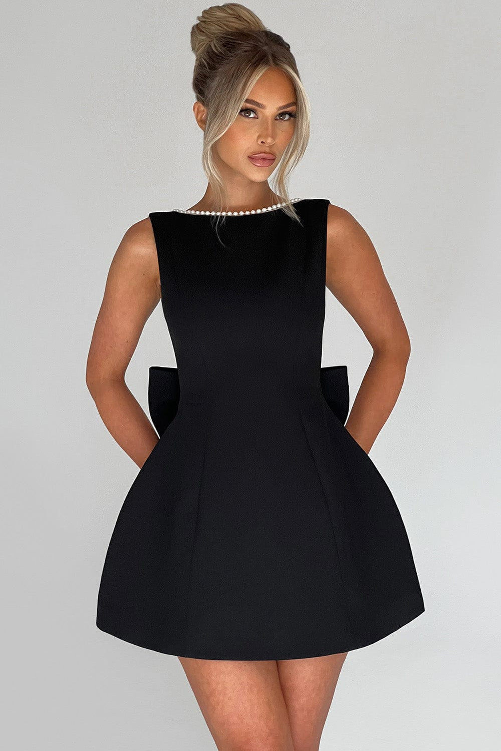Backless women's party mini dress with elegant pearl trim and a dramatic statement bow for special events.