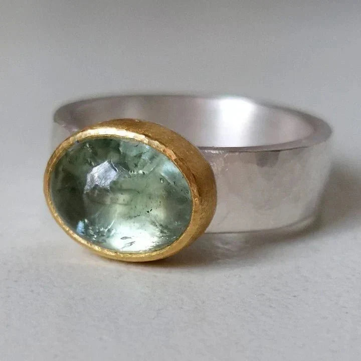 Women's artisan oval aquamarine gemstone ring with gold bezel setting on sterling silver mixed metal band.