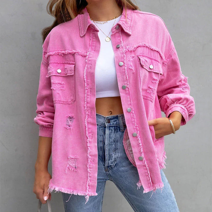Close-up of the distressed fraying details on a trendy women's denim jacket, ideal for edgy fashion.