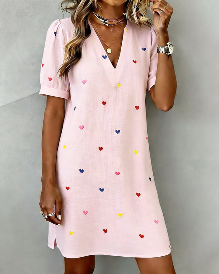 Cute women's casual dress with a vibrant heart print, V-neck, and chic puff sleeves for warm weather.