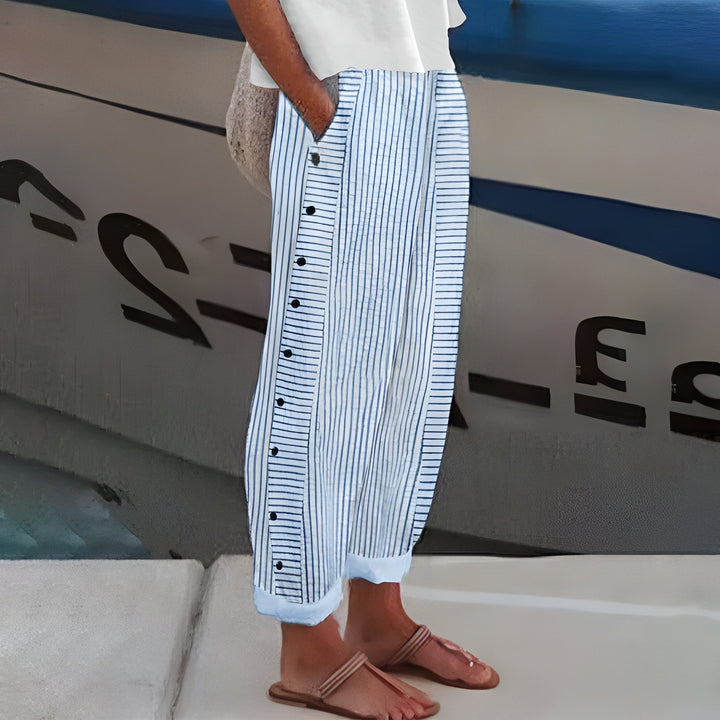 Women's chic black cropped trousers with white stripe detail and decorative buttons, perfect for smart casual spring.