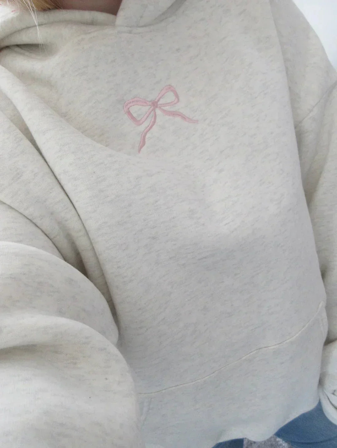 Women's chic hoodie with elegant bow detail on drawstring hood, offering stylish comfort and a relaxed fit.
