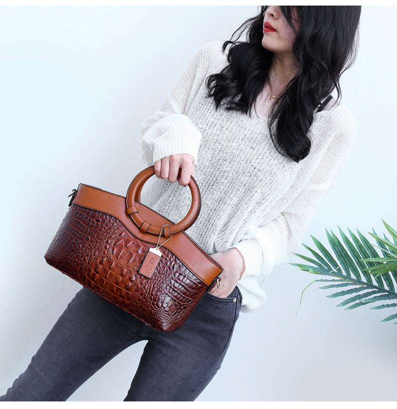Front view: Women's croc embossed vintage handbag with a distinctive round top handle.