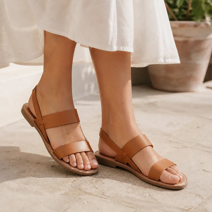 Stylish women's flat sandals with a chic crossover strap, perfect for warm weather.