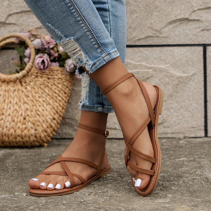 Trendy women's open-toe flat sandals with crossover toe loop and ankle strap for stylish summer comfort.