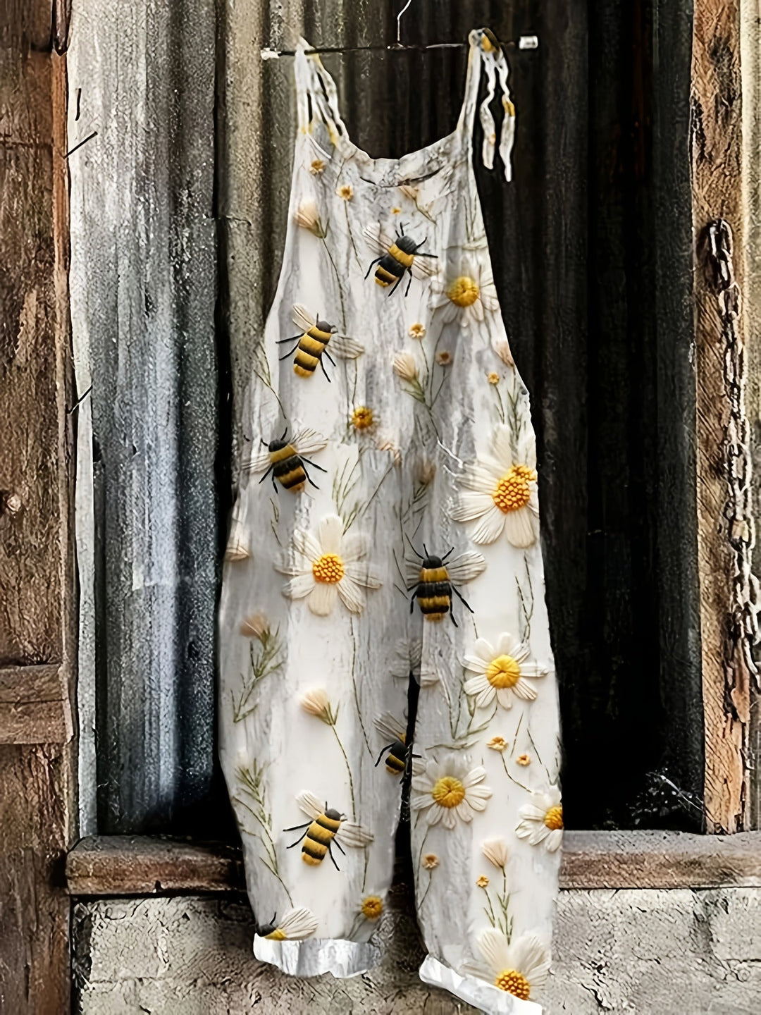 Relaxed fit women's tie shoulder jumpsuit featuring a charming daisy and bee print.