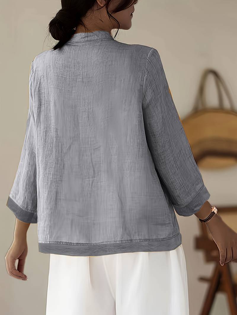 Detailed shot of the elegant frog button closure on a women's mandarin collar blouse.