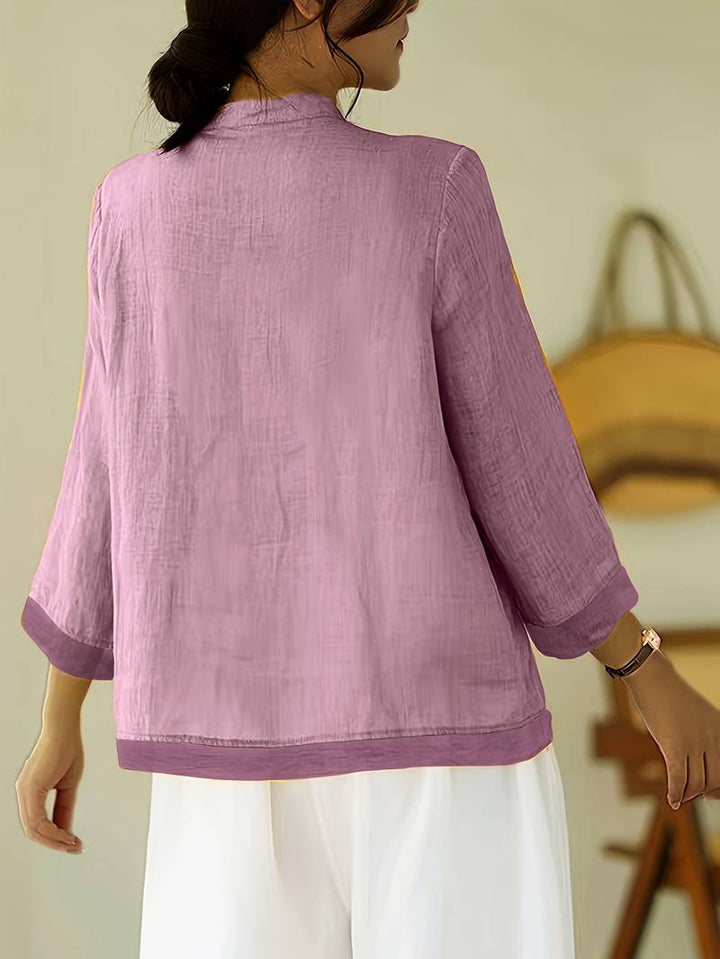 Elegant women's blouse with three-quarter sleeves, mandarin collar, and distinctive frog buttons.